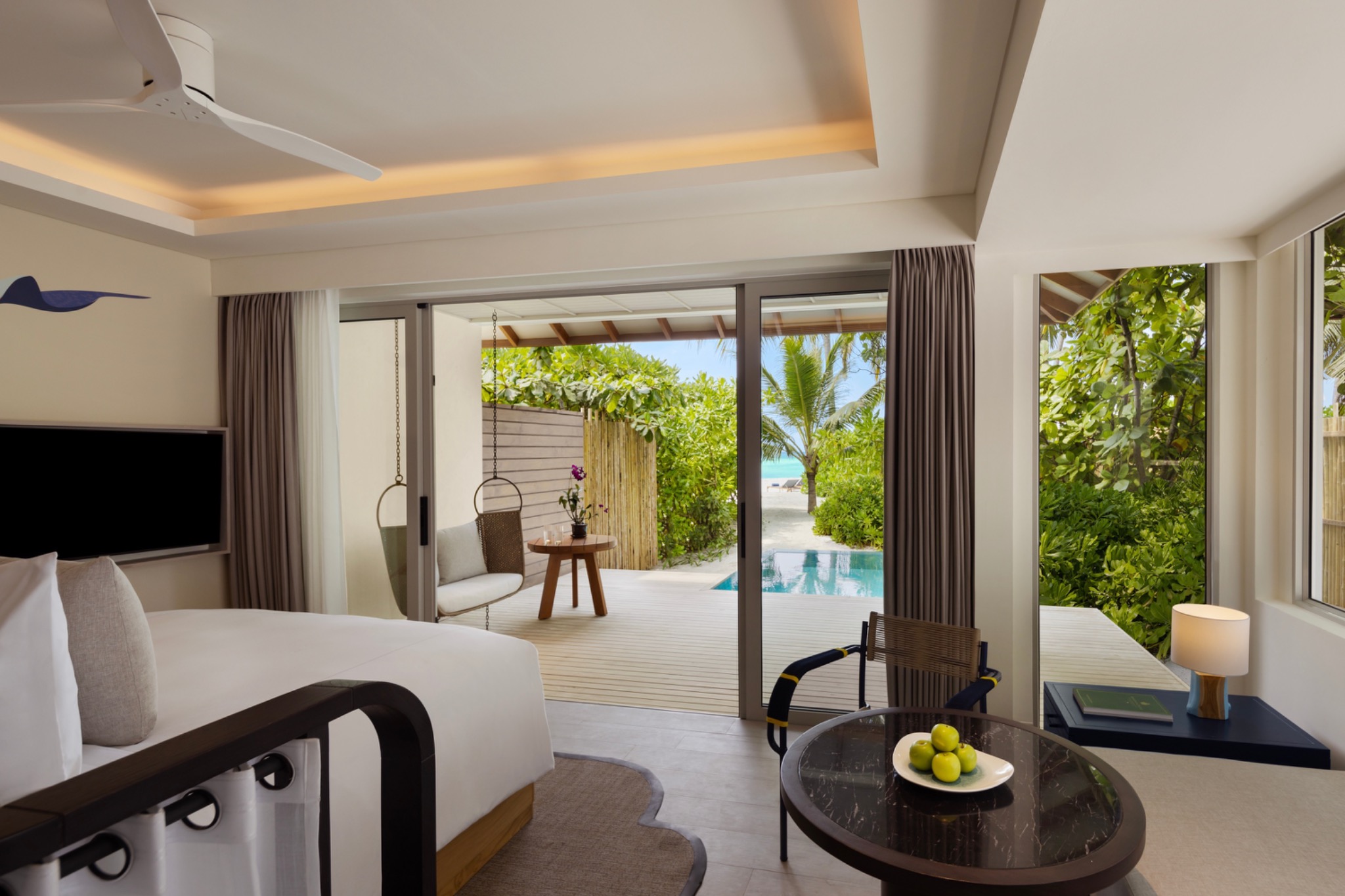 Schlafzimmer mit Blick auf Pool und Strand im Avani+ Fares Maldives Resort