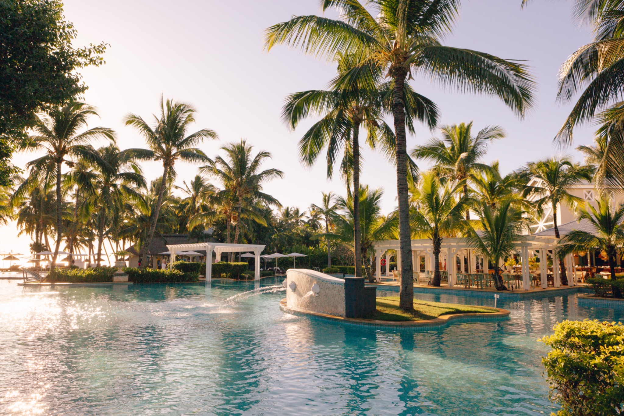 Poolanlage mit Palmen im Abendlicht im Sugar Beach Mauritius
